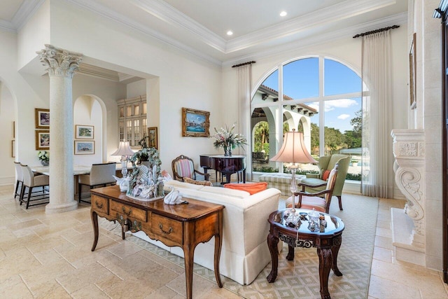 living area with arched walkways, a towering ceiling, crown molding, and decorative columns