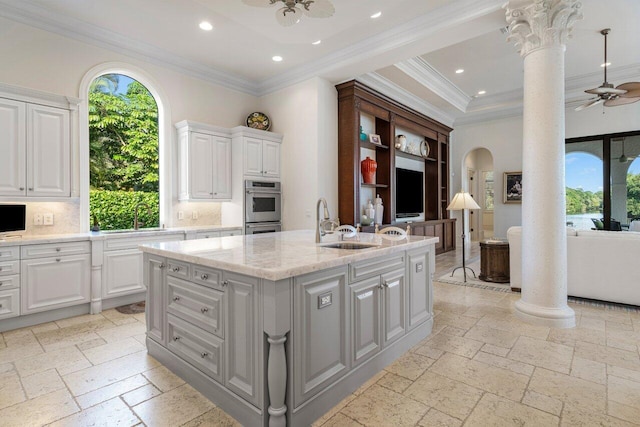 kitchen featuring double oven, stone tile flooring, ceiling fan, recessed lighting, and ornate columns