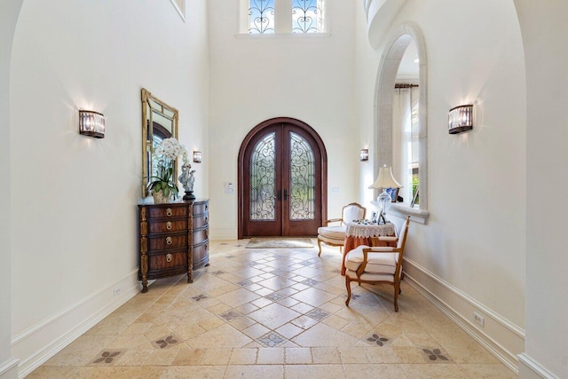 entrance foyer featuring arched walkways, a healthy amount of sunlight, baseboards, and french doors