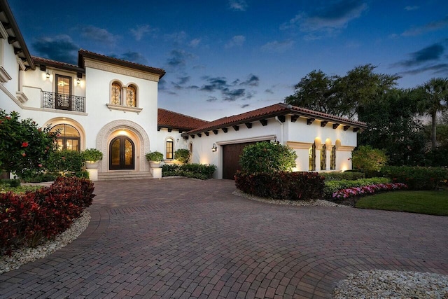 mediterranean / spanish-style home with a garage, a balcony, and french doors