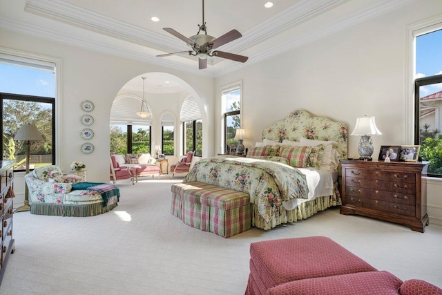 carpeted bedroom featuring crown molding, a tray ceiling, recessed lighting, arched walkways, and ceiling fan