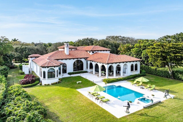 rear view of property featuring a patio, a tile roof, stucco siding, and a yard