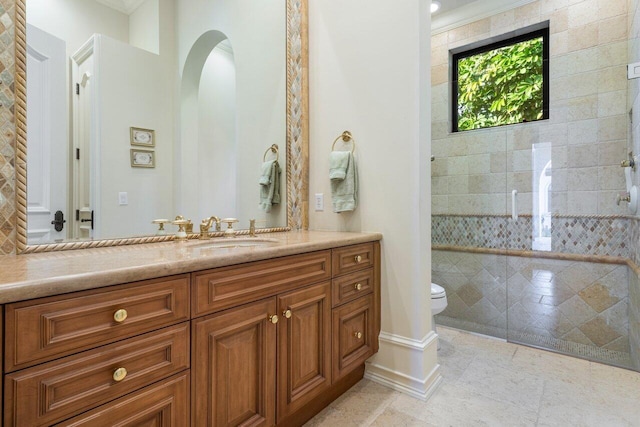 bathroom featuring toilet, vanity, baseboards, and a tile shower
