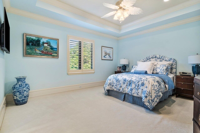 carpeted bedroom with a tray ceiling, baseboards, crown molding, and a ceiling fan