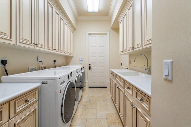 clothes washing area with crown molding, stone tile floors, a sink, separate washer and dryer, and cabinet space