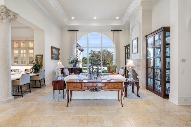 dining room featuring a raised ceiling, crown molding, a high ceiling, and ornate columns