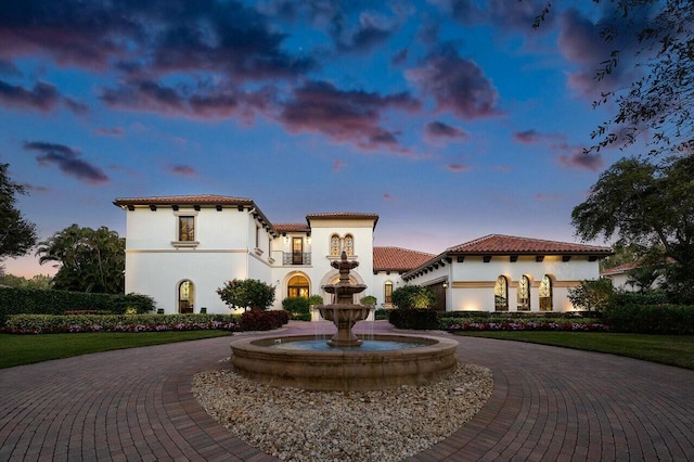 mediterranean / spanish home with a tile roof, curved driveway, and stucco siding