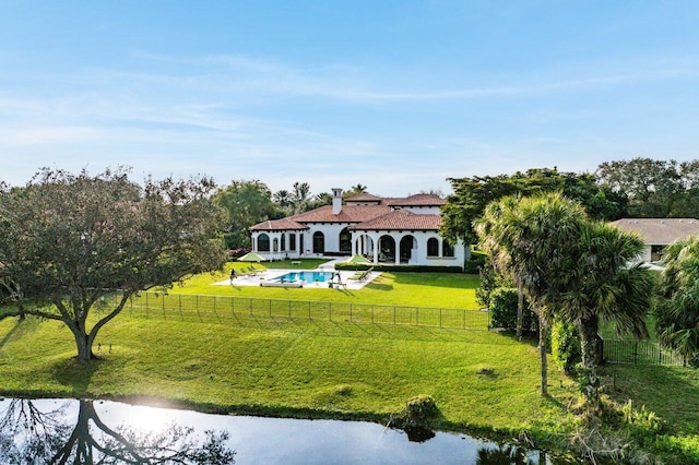 rear view of house with a fenced in pool and a lawn