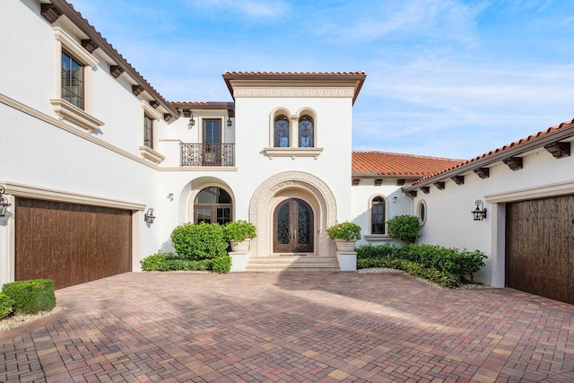 mediterranean / spanish house featuring french doors, a balcony, and a garage