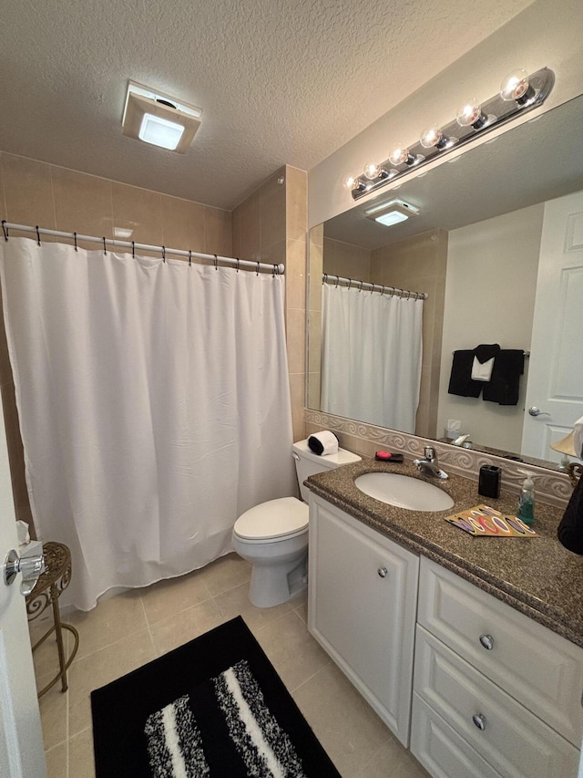 bathroom featuring a shower with shower curtain, vanity, a textured ceiling, tile patterned floors, and toilet