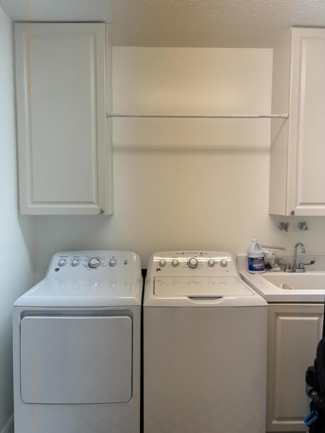 laundry area featuring sink, washing machine and dryer, and cabinets