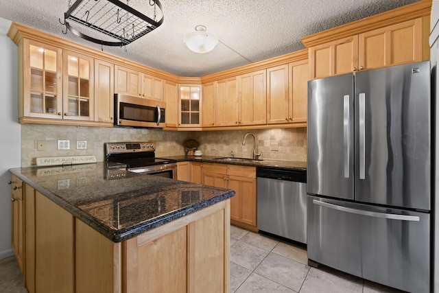 kitchen featuring light tile patterned flooring, appliances with stainless steel finishes, sink, dark stone countertops, and kitchen peninsula