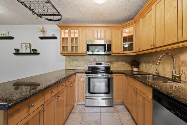 kitchen featuring light tile patterned flooring, sink, a textured ceiling, dark stone countertops, and stainless steel appliances