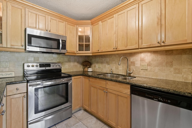 kitchen featuring light tile patterned flooring, sink, a textured ceiling, appliances with stainless steel finishes, and dark stone counters