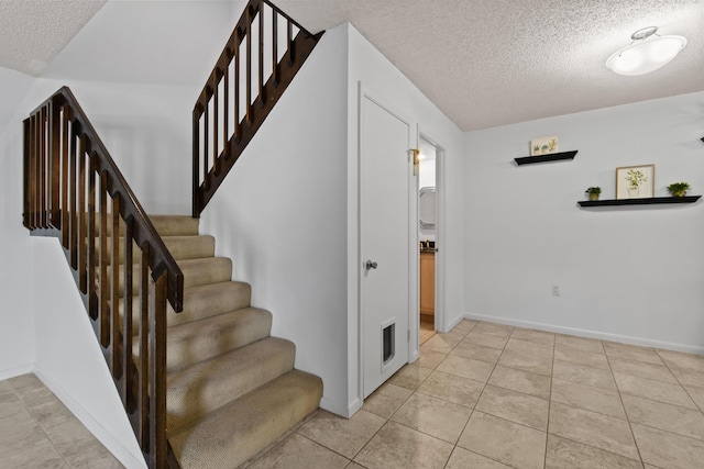 staircase with tile patterned flooring and a textured ceiling