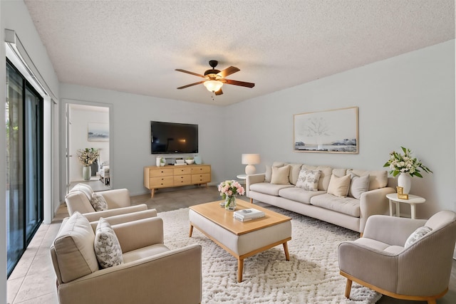 living room featuring ceiling fan, light tile patterned floors, and a textured ceiling