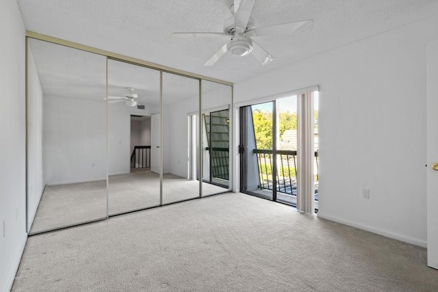 unfurnished bedroom with ceiling fan, a textured ceiling, access to outside, light colored carpet, and a closet