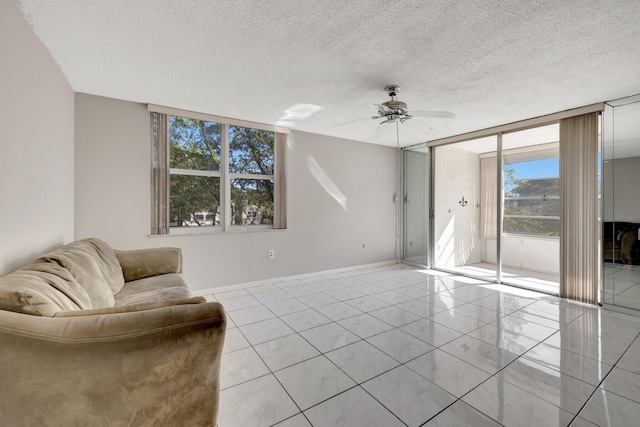 9101 Lime Bay Blvd Unit 312, Tamarac, FL 33321 - living area with a wall of windows, ceiling fan, a textured ceiling, baseboards, and light tile patterned floors