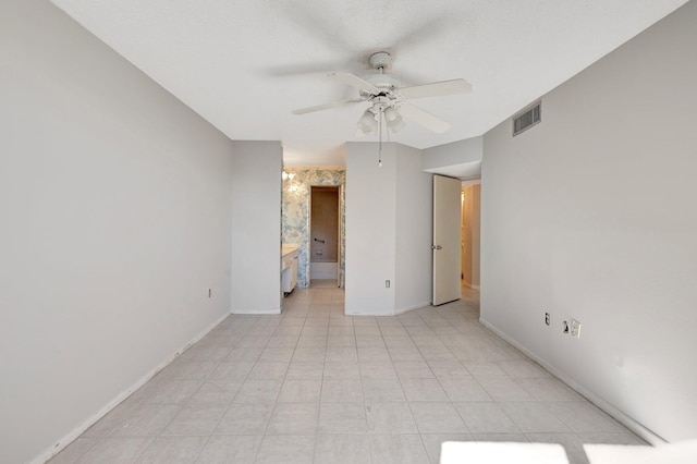 empty room with ceiling fan, visible vents, and baseboards