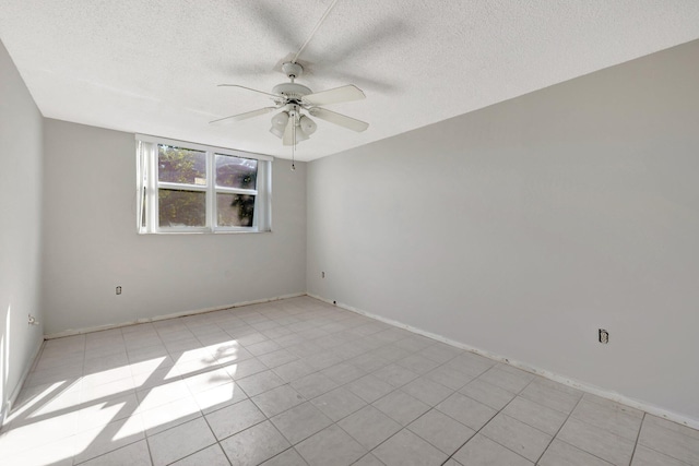 empty room featuring a ceiling fan, light tile patterned flooring, a textured ceiling, and baseboards