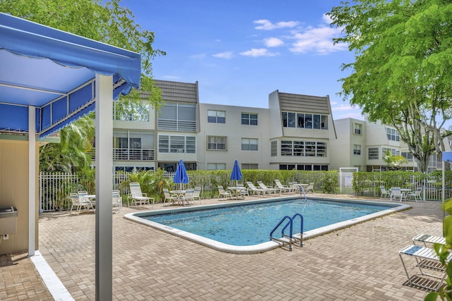 community pool with a patio and fence