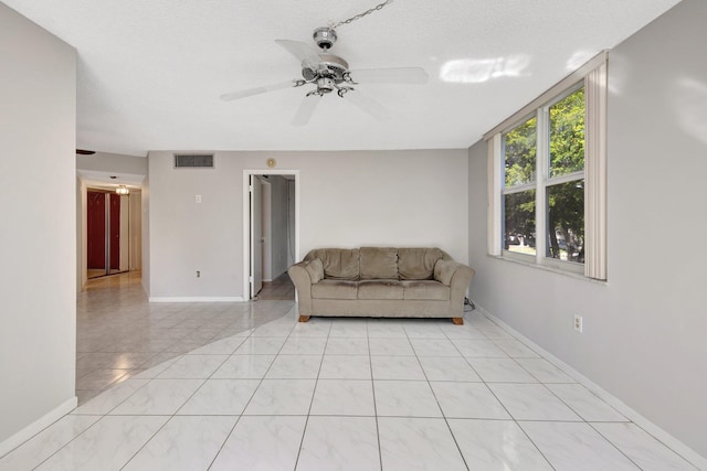 living room with baseboards, light tile patterned flooring, visible vents, and a ceiling fan