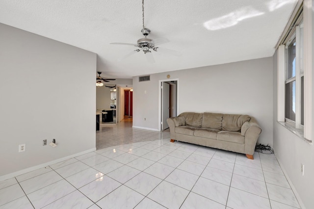 living room featuring light tile patterned floors, visible vents, a ceiling fan, a textured ceiling, and baseboards