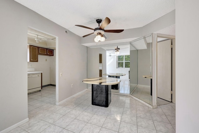 dining area with a textured ceiling, light tile patterned floors, and baseboards