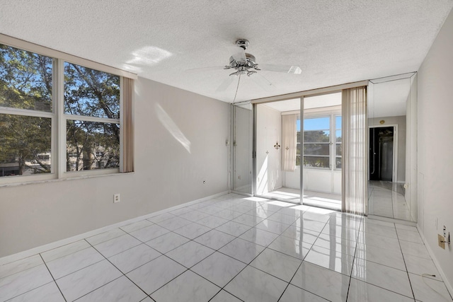 empty room featuring ceiling fan, a textured ceiling, baseboards, and light tile patterned floors