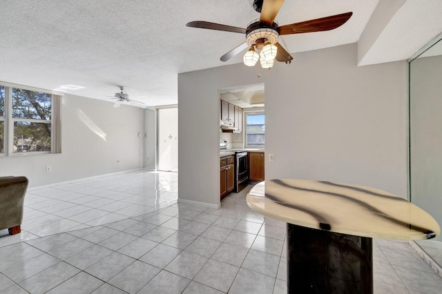 living room featuring light tile patterned floors, ceiling fan, a textured ceiling, and baseboards