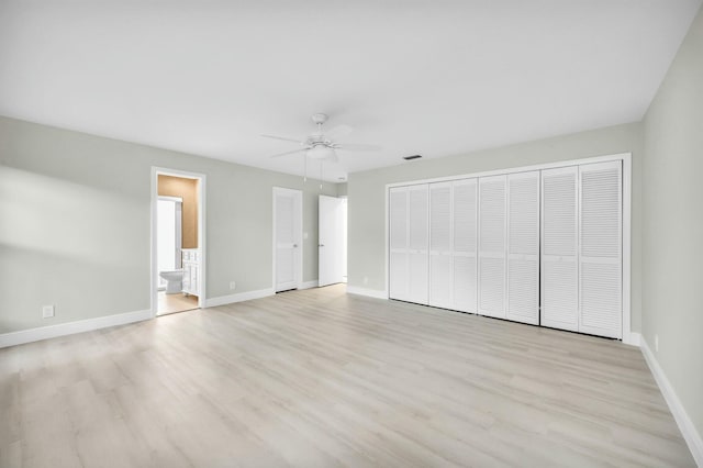 unfurnished bedroom featuring multiple closets, ceiling fan, ensuite bathroom, and light hardwood / wood-style flooring