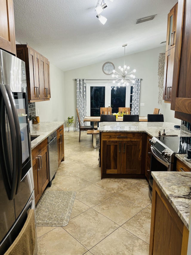 kitchen with lofted ceiling, light stone counters, kitchen peninsula, pendant lighting, and stainless steel appliances