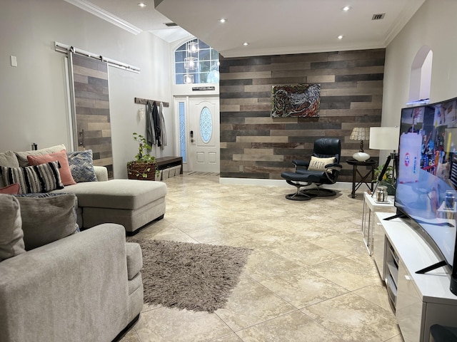 living room with a barn door, wooden walls, and crown molding