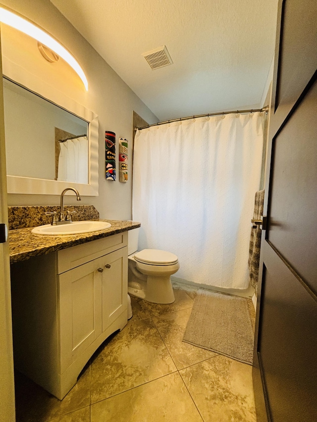 bathroom with vanity, a textured ceiling, and toilet