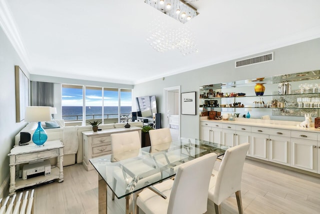 dining space with a notable chandelier, crown molding, and light hardwood / wood-style floors