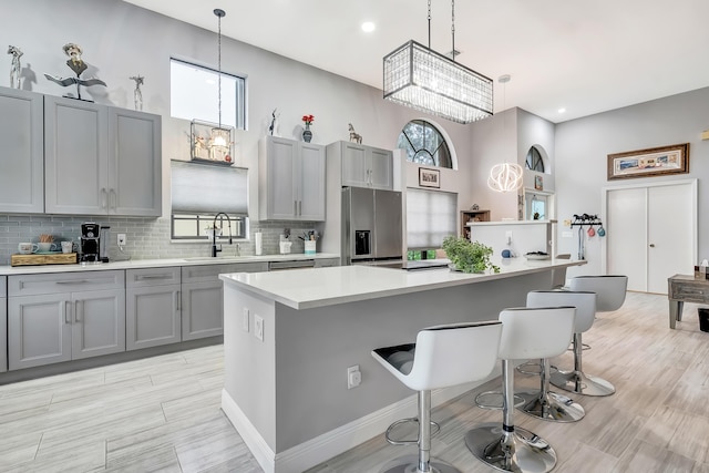 kitchen with stainless steel fridge with ice dispenser, sink, pendant lighting, and a center island