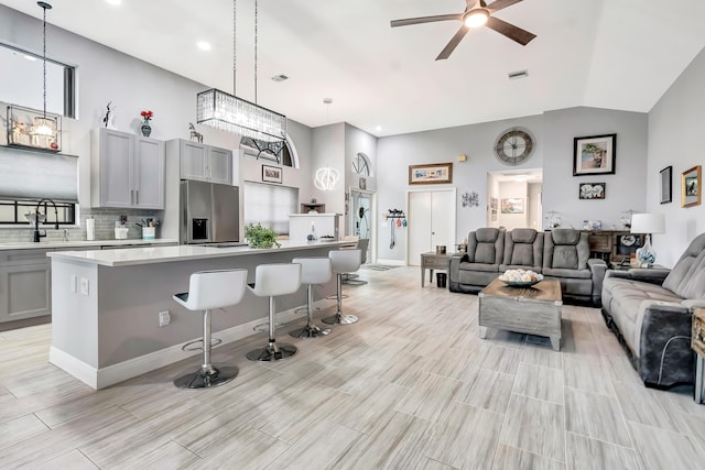 kitchen featuring a kitchen bar, stainless steel fridge with ice dispenser, a kitchen island, and gray cabinetry