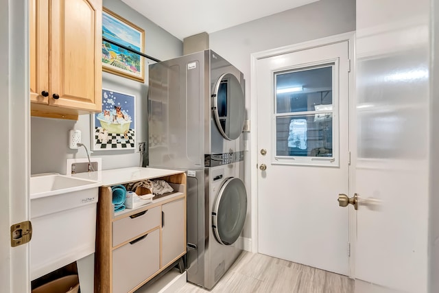 washroom with stacked washer / drying machine, sink, and cabinets