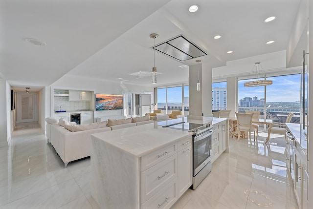 kitchen featuring pendant lighting, white cabinetry, a center island, a wealth of natural light, and stainless steel electric stove