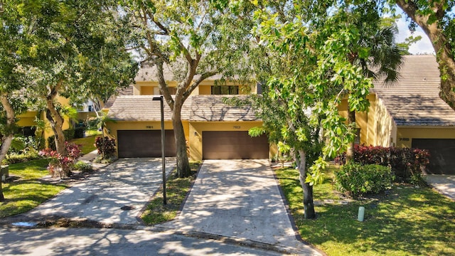 view of front facade with a garage, driveway, and stucco siding