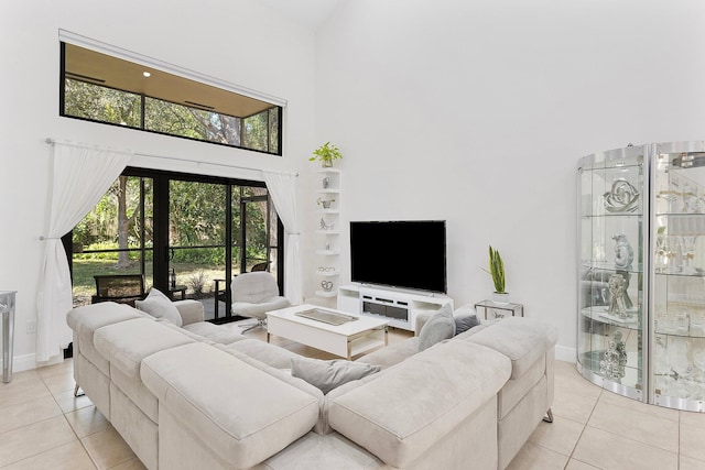 living room with a towering ceiling, baseboards, and light tile patterned floors