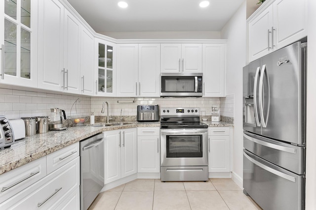 kitchen featuring stainless steel appliances, a sink, glass insert cabinets, and white cabinets