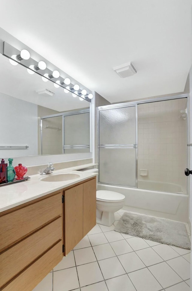 full bathroom with tile patterned flooring, bath / shower combo with glass door, vanity, and toilet