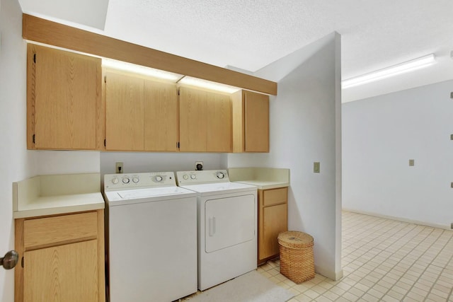 clothes washing area featuring washing machine and dryer, cabinets, and a textured ceiling