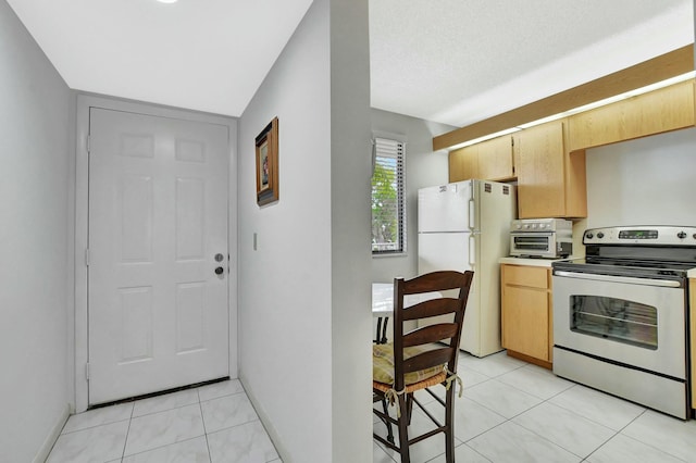 kitchen featuring stainless steel range with electric stovetop, light tile patterned flooring, a textured ceiling, and white refrigerator