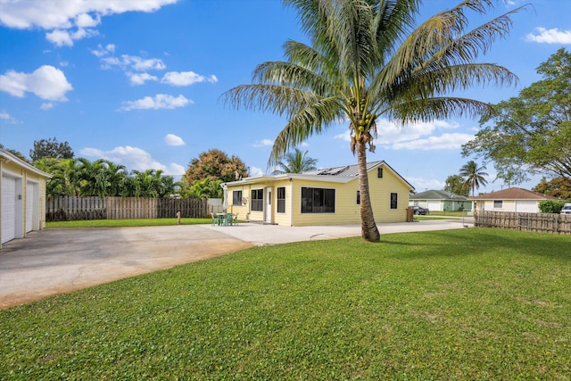 rear view of house featuring a patio, a lawn, and solar panels