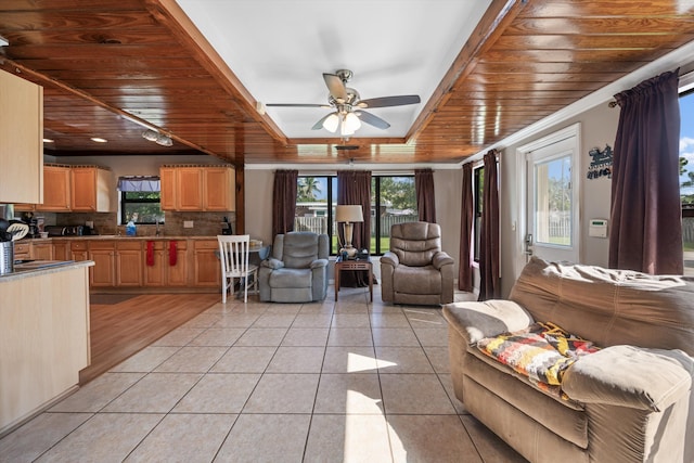 living room with light tile patterned floors, plenty of natural light, wooden ceiling, and a raised ceiling