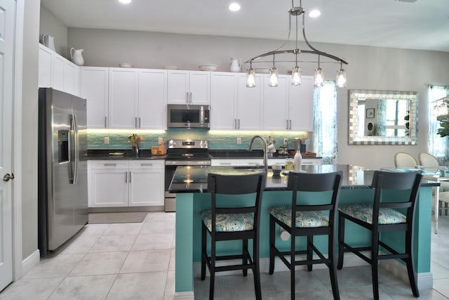 kitchen with stainless steel appliances, a breakfast bar, hanging light fixtures, and white cabinets