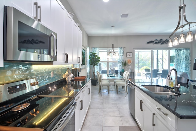 kitchen with appliances with stainless steel finishes, pendant lighting, sink, white cabinets, and light tile patterned floors