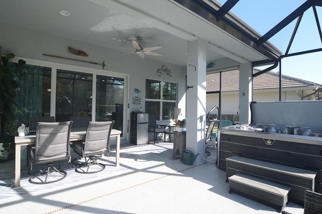 view of patio / terrace featuring a hot tub, ceiling fan, and glass enclosure